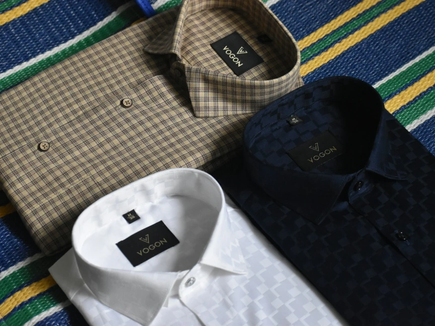 a variety of men's shirts laid out on a bed